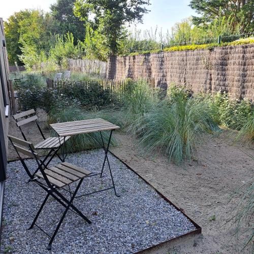 a picnic table and two chairs in a garden at Dunehuys in Koksijde