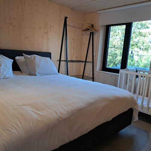 a bedroom with a large white bed with a window at Dunehuys in Koksijde