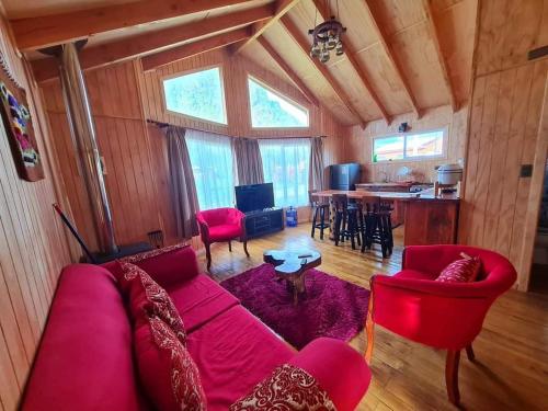 sala de estar con sofá rojo y mesa en Cabañas Villa Elfo, en Futrono