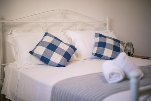 a white bed with blue and white pillows at Villa del Mirto a 300mt dalla spiaggia, parcheggio privato, animali ammessi in Torre Santa Sabina