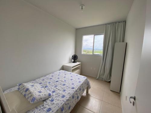 um pequeno quarto com uma cama e uma janela em Ape praia de fora de frente do mar em Palhoça