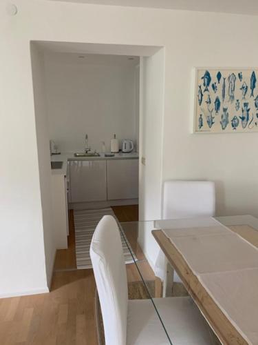 a dining room with a glass table and white chairs at Hof Am Bach in Caldaro