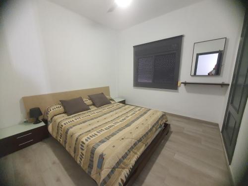 ein Schlafzimmer mit einem Bett und einem TV an der Wand in der Unterkunft Apartamento a 100 metros de la playa in Piles