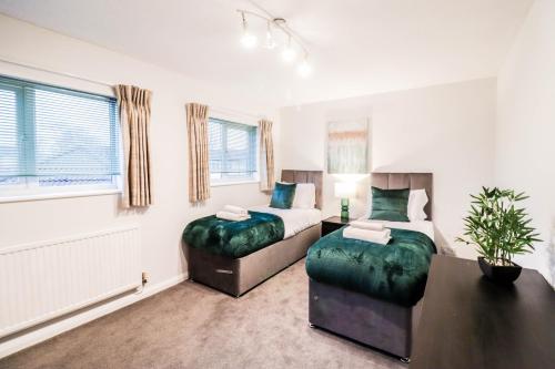 ein Schlafzimmer mit 2 Betten und einem Tisch mit einer Pflanze in der Unterkunft 2 Bedroom Flat - Close to BBC studios! in Borehamwood