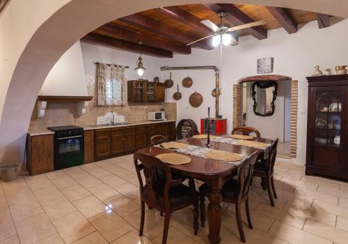 uma grande cozinha com uma mesa de madeira e cadeiras em Marcora's Historical Estate em Strongylí