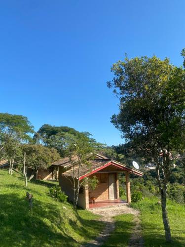 ein Gebäude auf einem grasbewachsenen Hügel mit einem Baum in der Unterkunft Pousada Chalés Vale do Sol in Conceição da Ibitipoca