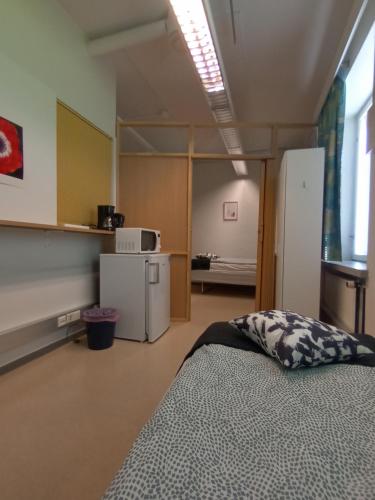 a room with a bed and a refrigerator in it at Hotelli Posti in Äänekoski