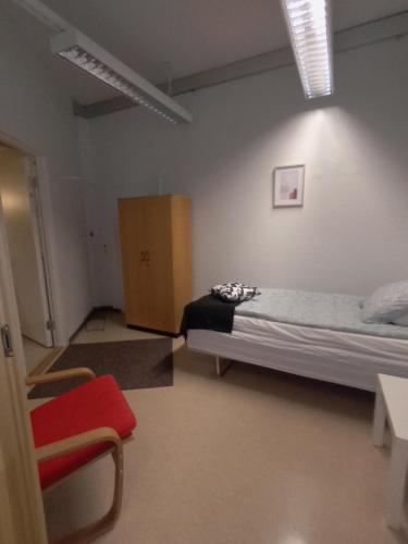 a bedroom with a bed and a red chair at Hotelli Posti in Äänekoski