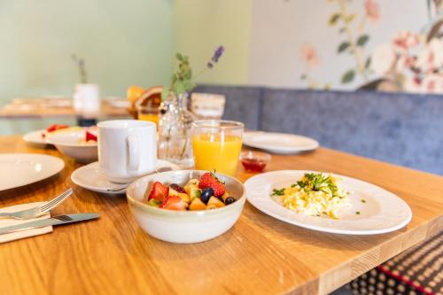 a table with plates of food and a bowl of fruit at Allgäu-Hotel-Elbsee in Aitrang