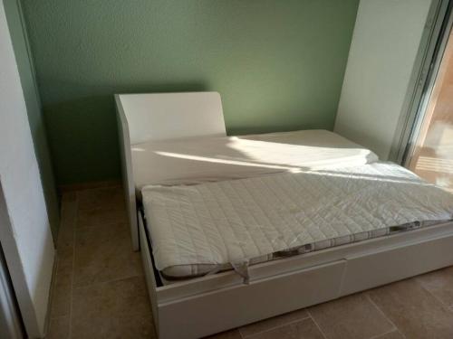 Cette chambre comprend un petit lit blanc et une fenêtre. dans l'établissement Beau Studio Mar Vivo, à La Seyne-sur-Mer