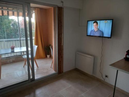 un salon avec une télévision à écran plat au mur dans l'établissement Beau Studio Mar Vivo, à La Seyne-sur-Mer