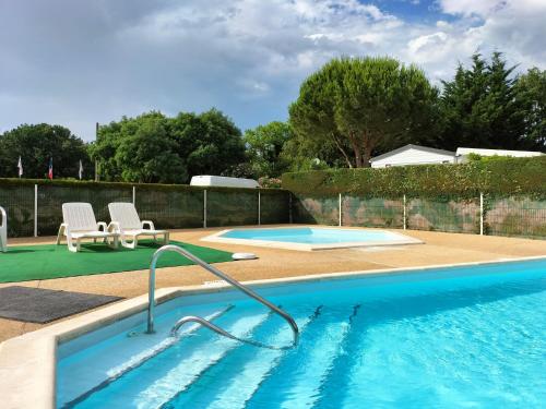 - une piscine avec 2 chaises à côté de la piscine dans l'établissement Coquillages & Crustacés avec Piscine Chauffée & Plage, à Marennes