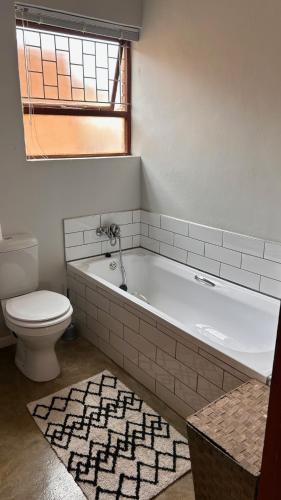 a bathroom with a white tub and a toilet at 28 Kabeljauws in Jeffreys Bay