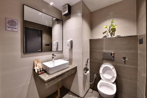 een badkamer met een wastafel, een toilet en een spiegel bij Click Sunburry Hotel Katra in Katra