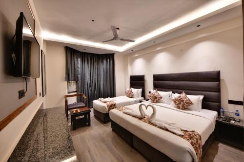 a hotel room with two beds and a flat screen tv at Click Sunburry Hotel Katra in Katra