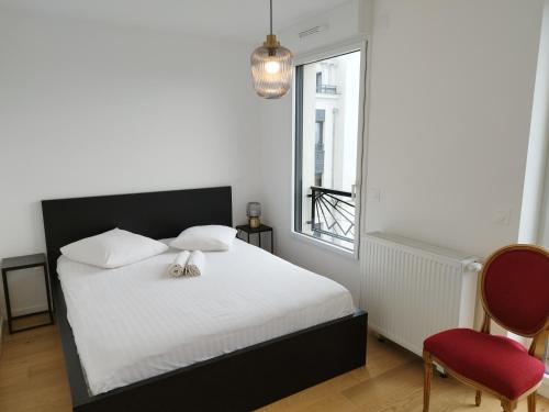 une chambre avec un lit blanc et une chaise rouge dans l'établissement Super Appart 4 p - à 5 min Disneyland, à Chessy