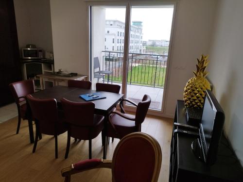 une salle à manger avec une table et des chaises et une grande fenêtre dans l'établissement Super Appart 4 p - à 5 min Disneyland, à Chessy