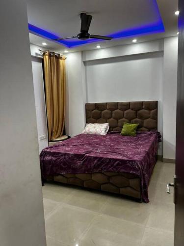a bedroom with a large bed with a purple blanket at exclusive apartment for bash in Faridabad