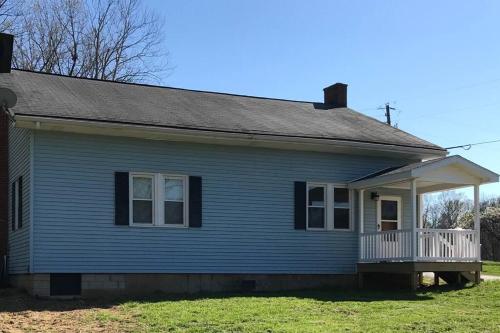 a blue house with a porch and a balcony at Caddy Corner has a hot tub just outside of town in French Lick