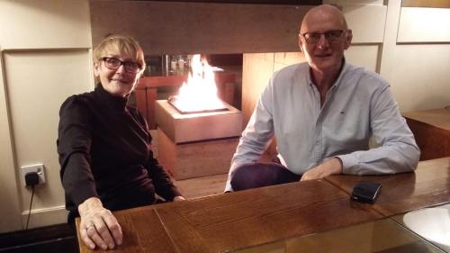 a man and woman sitting at a table in front of a fireplace at Woodview House Bed and Breakfast in Cork