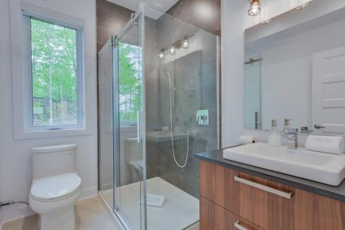 a bathroom with a shower and a toilet and a sink at Modern Chalet, 10 mins from Tremblant Ski Resort in La Conception