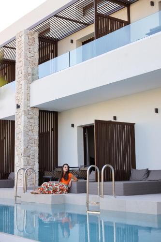 a woman sitting on a bed next to a swimming pool at LAN-GO SIVOTA Luxury Living in Sivota