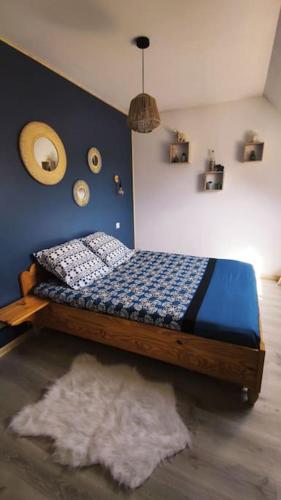 une chambre avec un lit avec un mur bleu dans l'établissement L'amour Breizh, à Plouaret