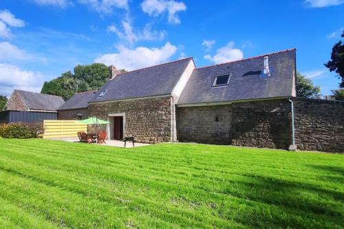 ein Steinhaus mit einem großen Rasenhof in der Unterkunft L'amour Breizh in Plouaret