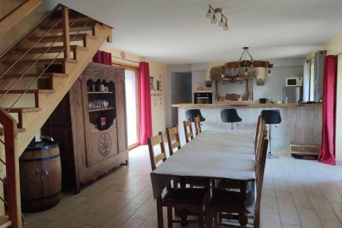 ein Esszimmer mit einem Tisch, Stühlen und einer Treppe in der Unterkunft L'amour Breizh in Plouaret