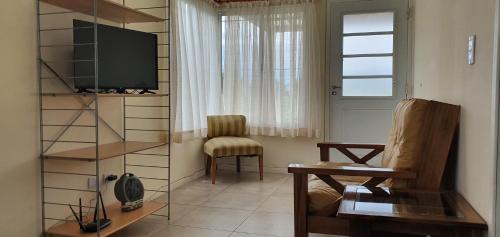 ein Wohnzimmer mit einem TV und einem Stuhl in der Unterkunft Casa con PILETA, PARRILLA y cochera cubierta in Chascomús