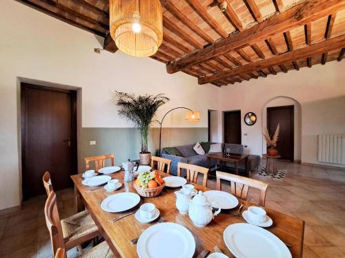 a dining room with a wooden table with white plates at Le Valli Tuscany in Pomarance