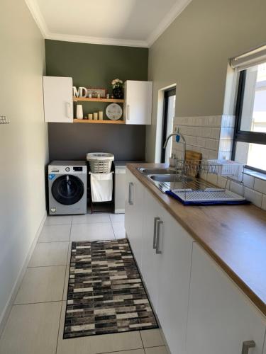 a kitchen with a sink and a washing machine at Family Friendly Home in Gordonʼs Bay