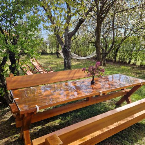 a wooden picnic table with a vase of flowers on it at Seoska kuca Stojanović in Kladovo