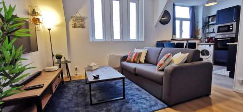 una sala de estar con un sofá y una mesa en Reims Appart - Idéal pour Pro en déplacement *Wifi rapide *Vue panoramique *Parking facile, en Roubaix