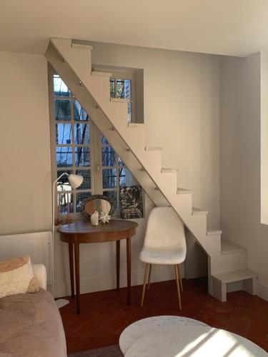 a room with a staircase and a table and a chair at O DELA DE L'O, LE 64 - maison d'hôtes de charme entre Côte d'Albâtre et Baie de Somme in Eu