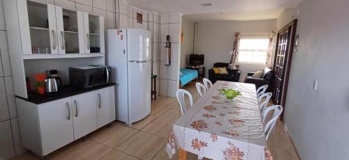 uma cozinha com uma mesa e um frigorífico branco em Ap térreo a 50 metros do mar em Balneário Gaivotas