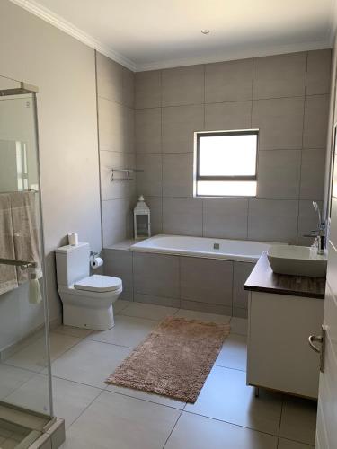 a bathroom with a tub and a toilet and a sink at Family Friendly Home in Gordonʼs Bay