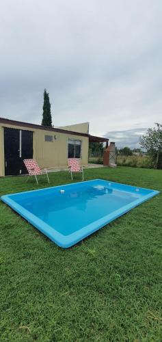 a large blue trampoline in a yard with two chairs at Casa con PILETA, PARRILLA y cochera cubierta in Chascomús