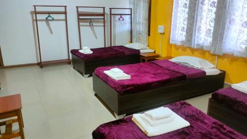 three beds in a room with purple sheets at Iranyai Homestay in Imphal