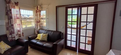 a living room with two leather chairs and a sliding glass door at A beira mar,2quarto,ar cond,garagem,ap terreo in Balneário Gaivotas