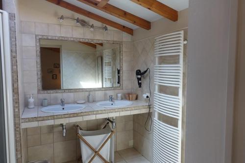 een badkamer met 2 wastafels en een spiegel bij Villa au bord de la mer, piscine chauffée 9x4 in Labenne