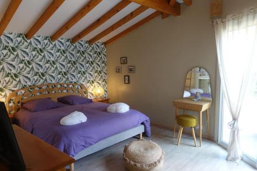een slaapkamer met een paars bed en een tafel bij Villa au bord de la mer, piscine chauffée 9x4 in Labenne