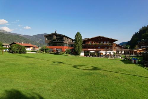 a large field of green grass with buildings in the background at Ferienwohnungen Karlingerhof am See in Achenkirch