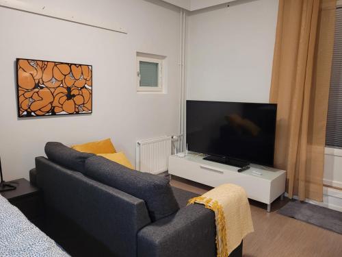a living room with a couch and a flat screen tv at Moderni ja supermukava asunto! 65'Smart TV, Valokuitunetti, lähellä yliopistoa! in Lappeenranta