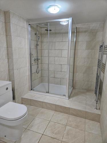 a bathroom with a shower and a toilet at Lister Park Bradford 2bed Detached Cottage House & Parking & Cinema Screen in Shipley