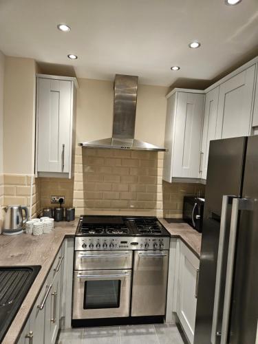 a kitchen with a stainless steel stove and white cabinets at Lister Park Bradford 2bed Detached Cottage House Parking Cinema Screen Games Room in Bradford
