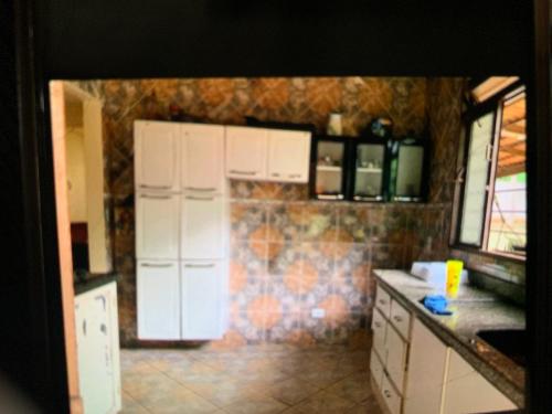 a kitchen with white cabinets and a tile wall at Recanto Abadia in Ribeirão