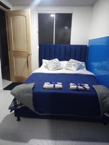 Una cama azul con dos pares de zapatillas. en House Beautiful Horizon P1, en Bogotá