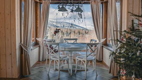 jadalnia ze stołem i krzesłami oraz dużym oknem w obiekcie Na Jeżynowej Polanie z gorącą balia w Wetlinie