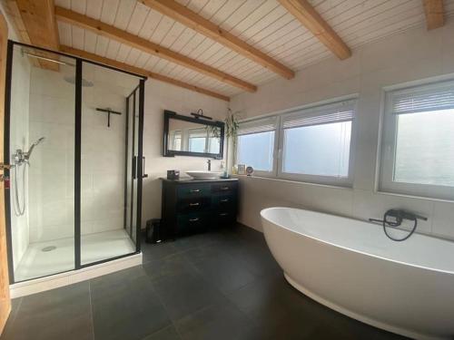 ein Bad mit einer Badewanne, einer Dusche und einem Waschbecken in der Unterkunft Ferienhaus Naturregion Sieg bis 6 Personen in Windeck